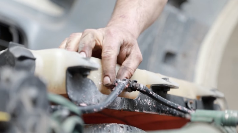 Detailed view of a technician securing fluid reservoir hoses on a truck